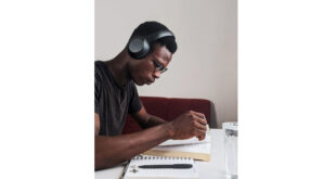 Exam study tips. Man wearing black crew neck t shirt using black headphones reading book while sitting.