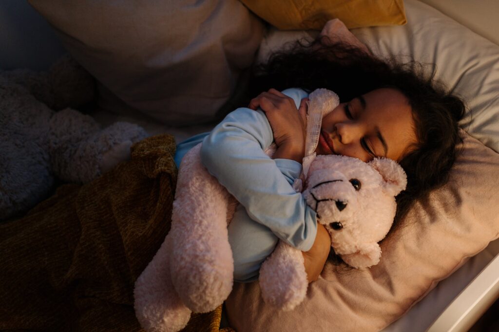 an adorable girl hugging her teddy bear while sleeping