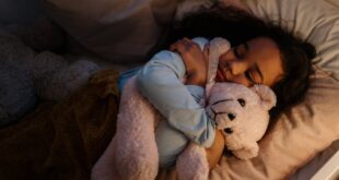 an adorable girl hugging her teddy bear while sleeping