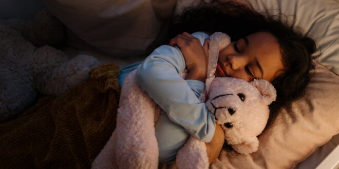 an adorable girl hugging her teddy bear while sleeping